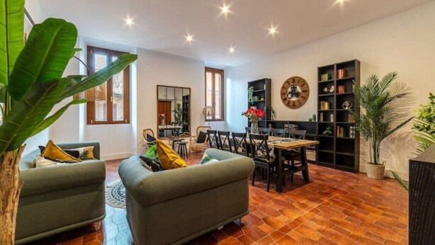 A spacious living area with a sofa, dining table, chairs, and a bookshelf. - New Charming Studio Unit in the Heart of Trastevere - Studio 4 (Roma)
