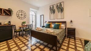 A bedroom with a bed, bedside table, and a small desk with chairs. There is a window with a view of the outside. - New Charming Studio Unit in the Heart of Trastevere - Studio 4 (Roma)