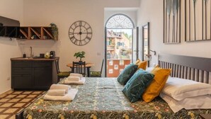 A bedroom with a bed, a clock, a desk, and a view of the outside. - New Charming Studio Unit in the Heart of Trastevere - Studio 4 (Roma)
