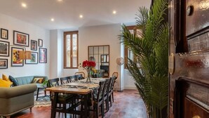 A dining area with a wooden table and chairs, a green sofa, and a large plant. - New Charming Studio Unit in the Heart of Trastevere - Studio 4 (Roma)