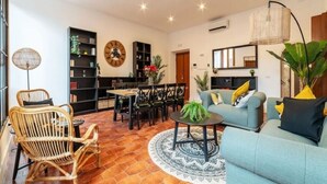 A living room with a sofa, chairs, a coffee table, a dining area with chairs and a table, a bookshelf, and a large clock on the wall. - New Charming Studio Unit in the Heart of Trastevere - Studio 4 (Roma)