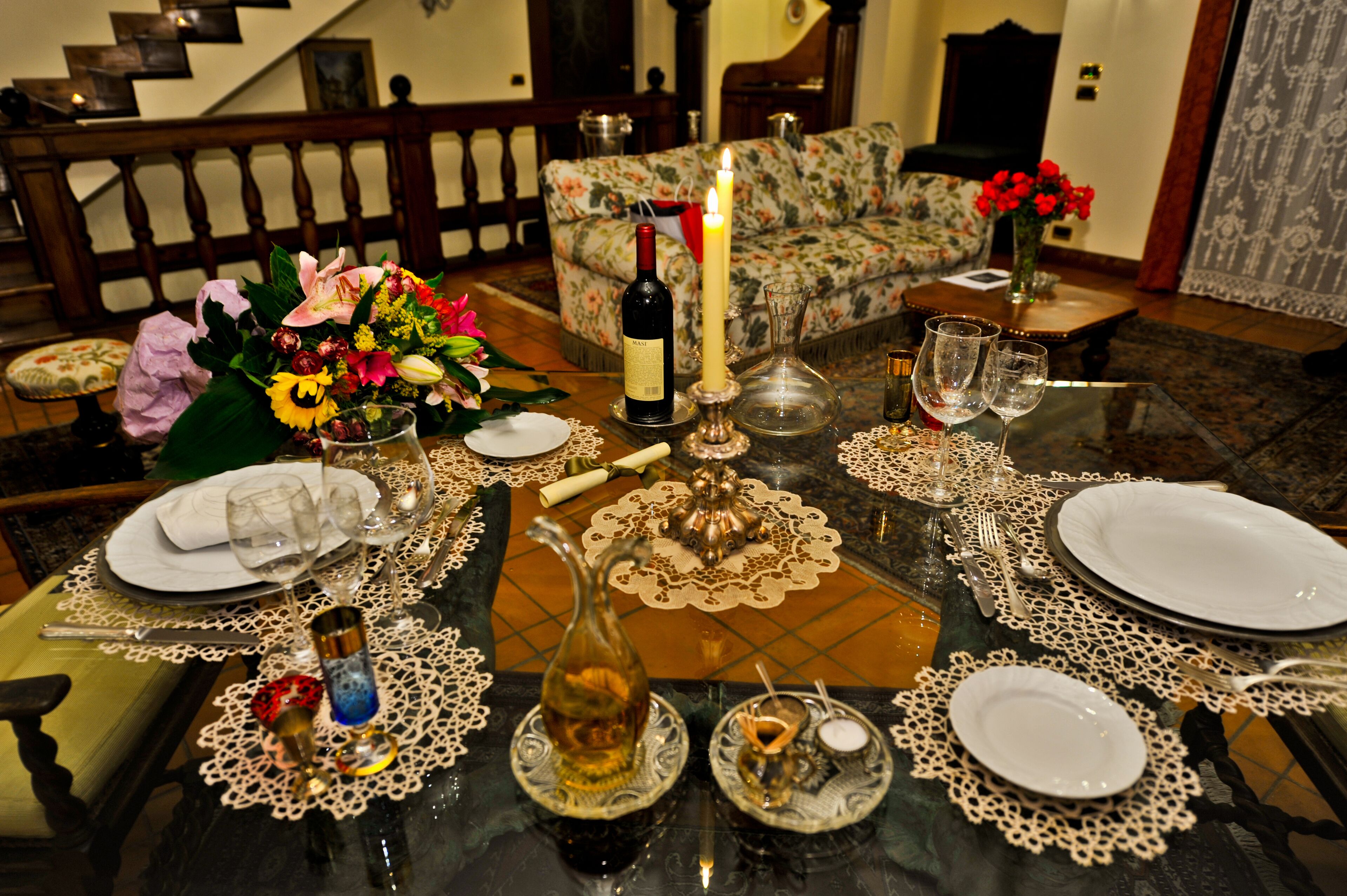 A dining table set for a meal with a candle, wine bottle, and various glassware.