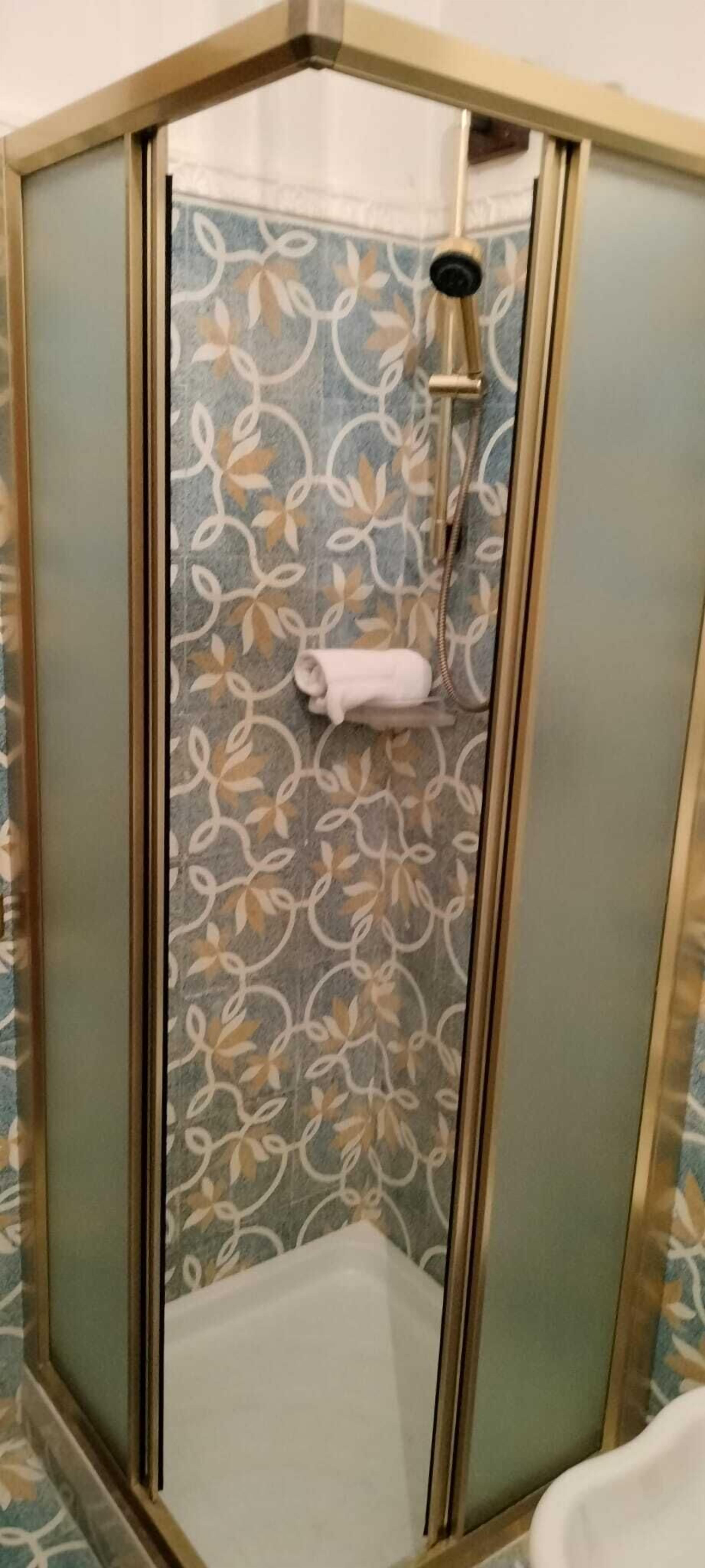 A shower with a glass door, a towel hanging on the wall, and a showerhead.