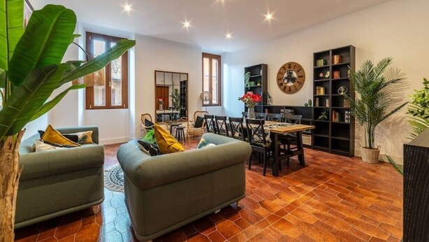 A spacious living room with a dining area, a large plant, and a bookshelf. - New Charming Studio Unit in the heart Of Trastevere - Studio 2 (Roma)