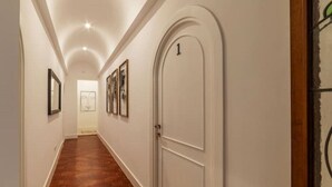 A hallway with a wooden floor, white walls, and a door marked with the number 1. - New Charming Studio Unit in the heart Of Trastevere - Studio 2 (Roma)