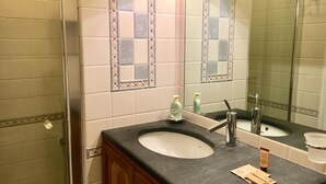 Une salle de bain avec un lavabo, un miroir et une douche.