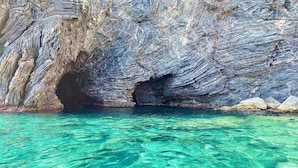 Une mer d’un bleu turquoise limpide, avec l’entrée d’une grotte rocheuse.