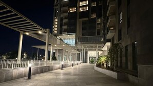A spacious outdoor area with a covered walkway, a building entrance, and a well-lit pathway. - ALSAWAH | Luxury 3BR Suite @Aeon Towers: Balcony & Skyline View (Giza Governorate)