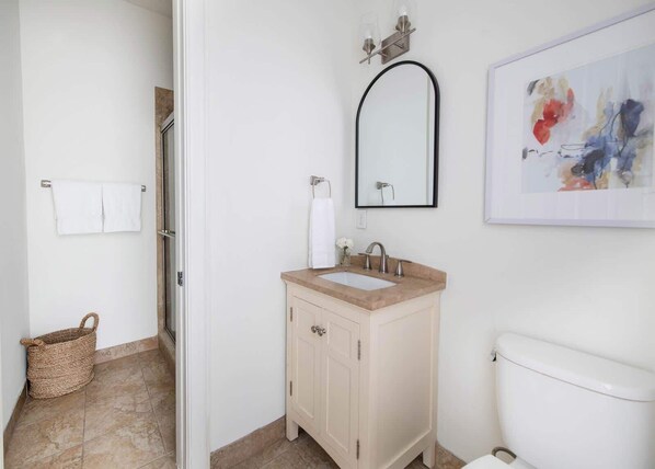 A bathroom with a beige vanity, a white toilet, and a wall-mounted mirror.