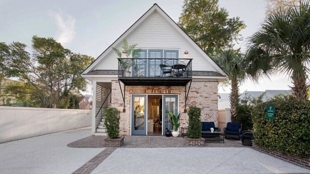 A two-story house with a balcony, a front door, and a small porch area with seating. - The Chapel | Manor 4BR Charming Charleston (Charleston)