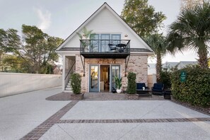 A two-story house with a balcony, a front door, and a small porch area with seating.