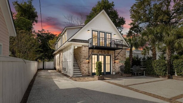 A two-story house with a stone facade, a balcony, and a front door with glass panels. - The Chapel | Grand 8BR Charmer - Walkable! (Charleston)