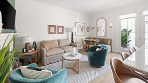 A modern living room with a sofa, armchairs, a coffee table, and a dining area with chairs and a table. - The Chapel | Grand 8BR Charmer - Walkable! (Charleston)