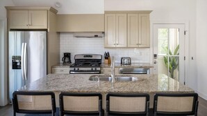 A kitchen with a central island, a stove, a refrigerator, and a sink. - The Chapel | Grand 8BR Charmer - Walkable! (Charleston)