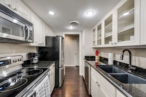 Una cocina moderna con electrodomésticos de acero inoxidable, encimera negra y armarios blancos.