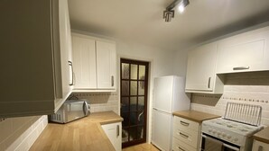 A kitchen with white cabinets, a microwave, a refrigerator, a stove, and a wooden countertop. - Serene 3/4BR in Harborne (Harborne)