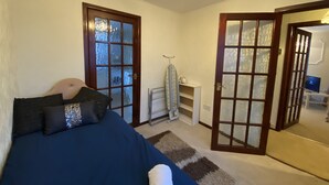 A bedroom with a bed, two doors, a radiator, and a TV. - Serene 3/4BR in Harborne (Harborne)