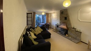 A living room with a sofa, a fireplace, and a dining area with a table and chairs. - Serene 3/4BR in Harborne (Harborne)