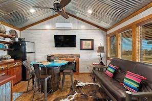 Un interior rústico con una zona de comedor, un sofá y un ventilador de techo.