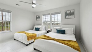 Ein Hotelzimmer mit zwei Betten, einem Deckenventilator und großen Fenstern.