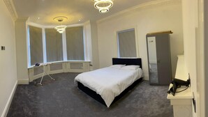 A bedroom with a bed, a vanity, a mirror, a wardrobe, a radiator, and a window with curtains. - Immaculate 1-bed Lux Apartment in Wolverhampton (Wolverhampton)