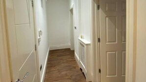 A narrow hallway with wooden flooring, white walls, and a white door at the end. - Immaculate 1-bed Lux Apartment in Wolverhampton (Wolverhampton)