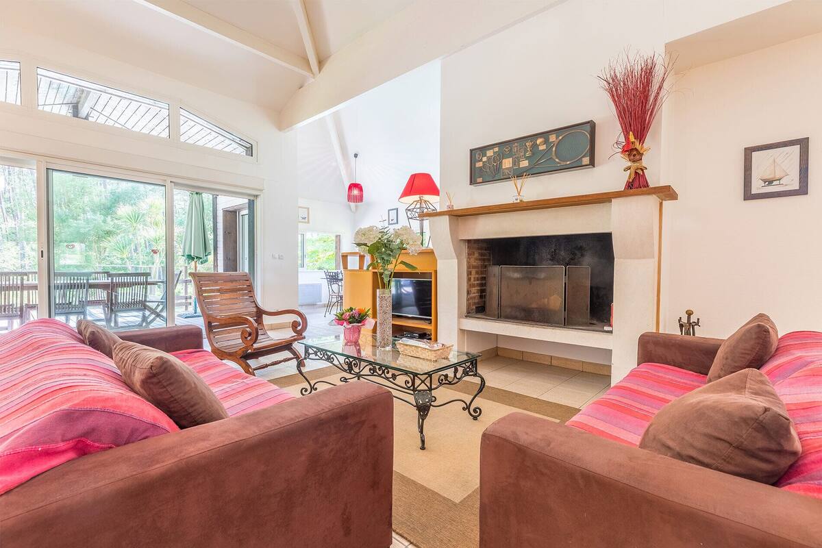 A spacious living room with a fireplace, comfortable seating, and a balcony with outdoor furniture.