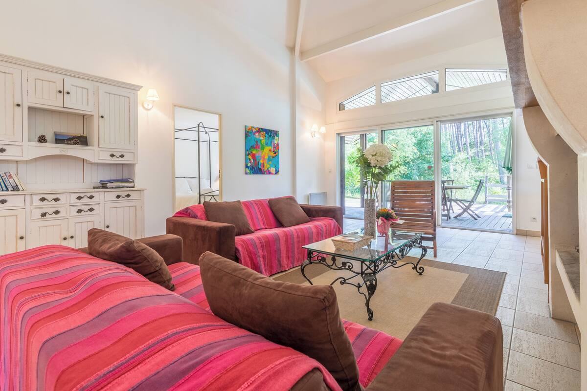 A spacious living area with a large bed, two sofas, a coffee table, and a view of the outdoors.