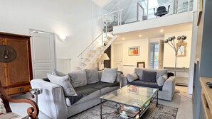 En moderne stue med sofa, sofabord og trappe op til en etage.
