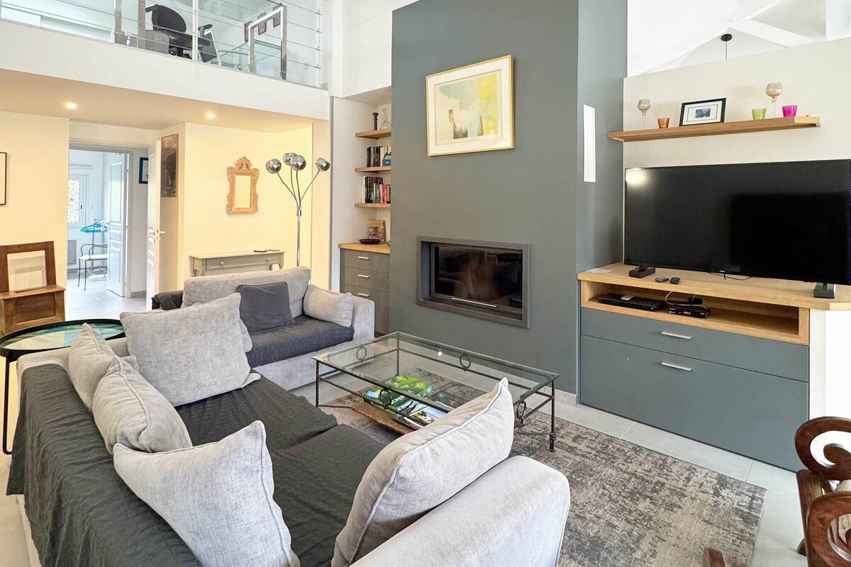 A modern living room with a sofa, coffee table, fireplace, TV, and bookshelves.