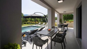 A modern outdoor patio with a pool, lounge chairs, and a dining table. - Stunning home in Labin (Labin)