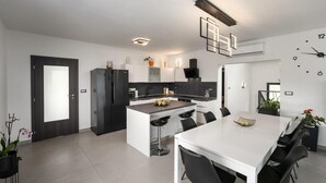 A modern kitchen with a central island, black chairs, and a white dining table. - Stunning home in Labin (Labin)