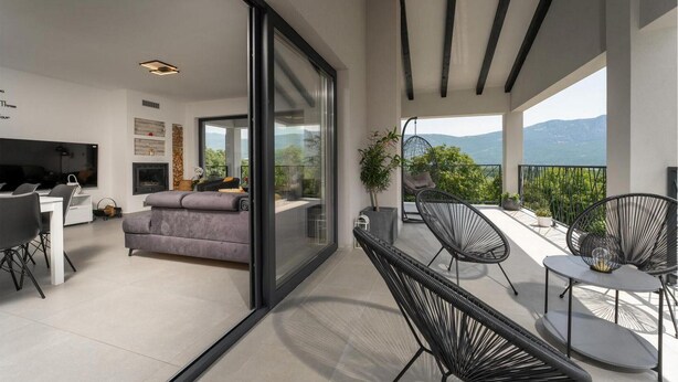 A modern living space with a balcony, a sofa, a dining area, and a view of mountains. - Stunning home in Labin (Labin)