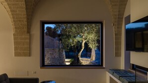 Ein modernes Wohnzimmer mit einem großen Fenster, das auf eine Steinmauer und einen Baum blickt.