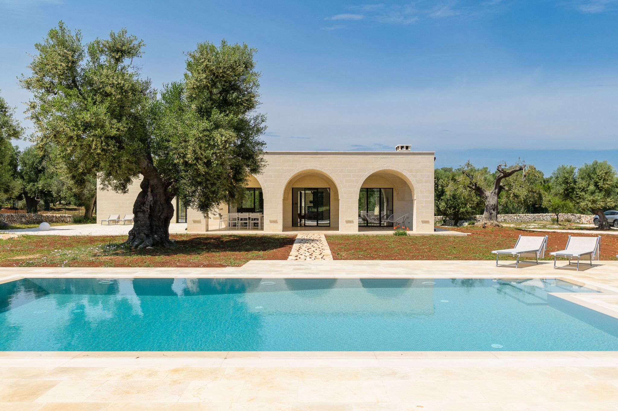 Eine moderne Villa mit Pool, Sitzgelegenheit im Freien und Meerblick.