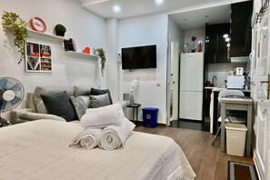 A modern hotel room with a bed, a TV, a small kitchen, and a fan. - HERMOSO APARTAMENTO TIPO ESTUDIO EN MADRID SFL5 (Madrid)