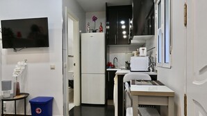Een compacte keuken met een koelkast, spoelbak en een klein eethoekje.