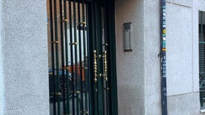 Een gevel met een groene poort, het cijfer '5' boven de ingang en een klein plaquette aan de muur.