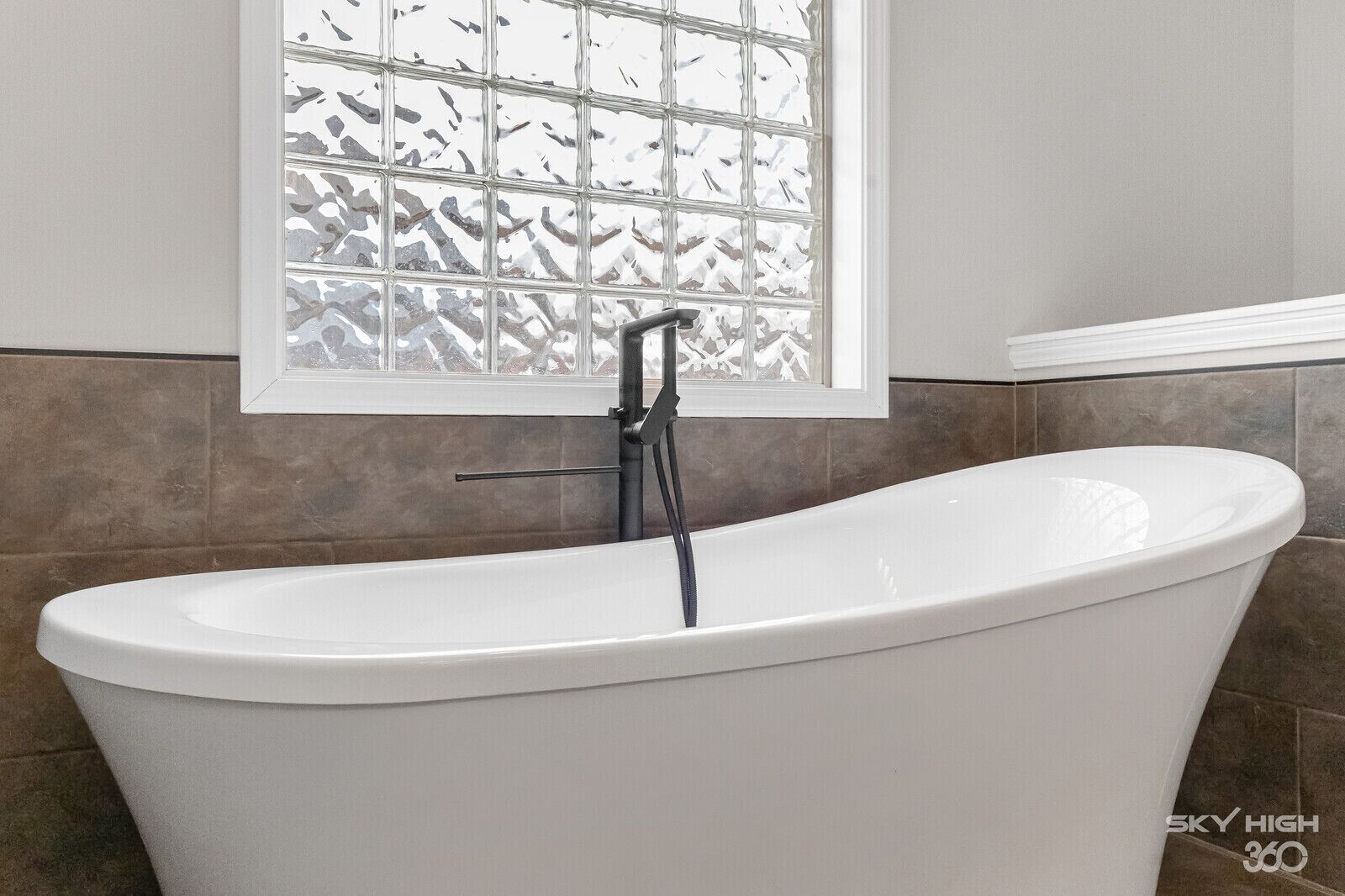 A freestanding bathtub in a bathroom with a window above it.