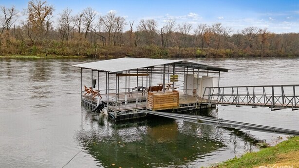 Un muelle flotante con una zona de estar cubierta y una cabaña de madera.
