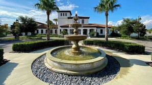 A fountain in a landscaped area with a building in the background. - Pool Privacy! Value! Resort 6 mi 2 Disney! 1712 (Kissimmee)