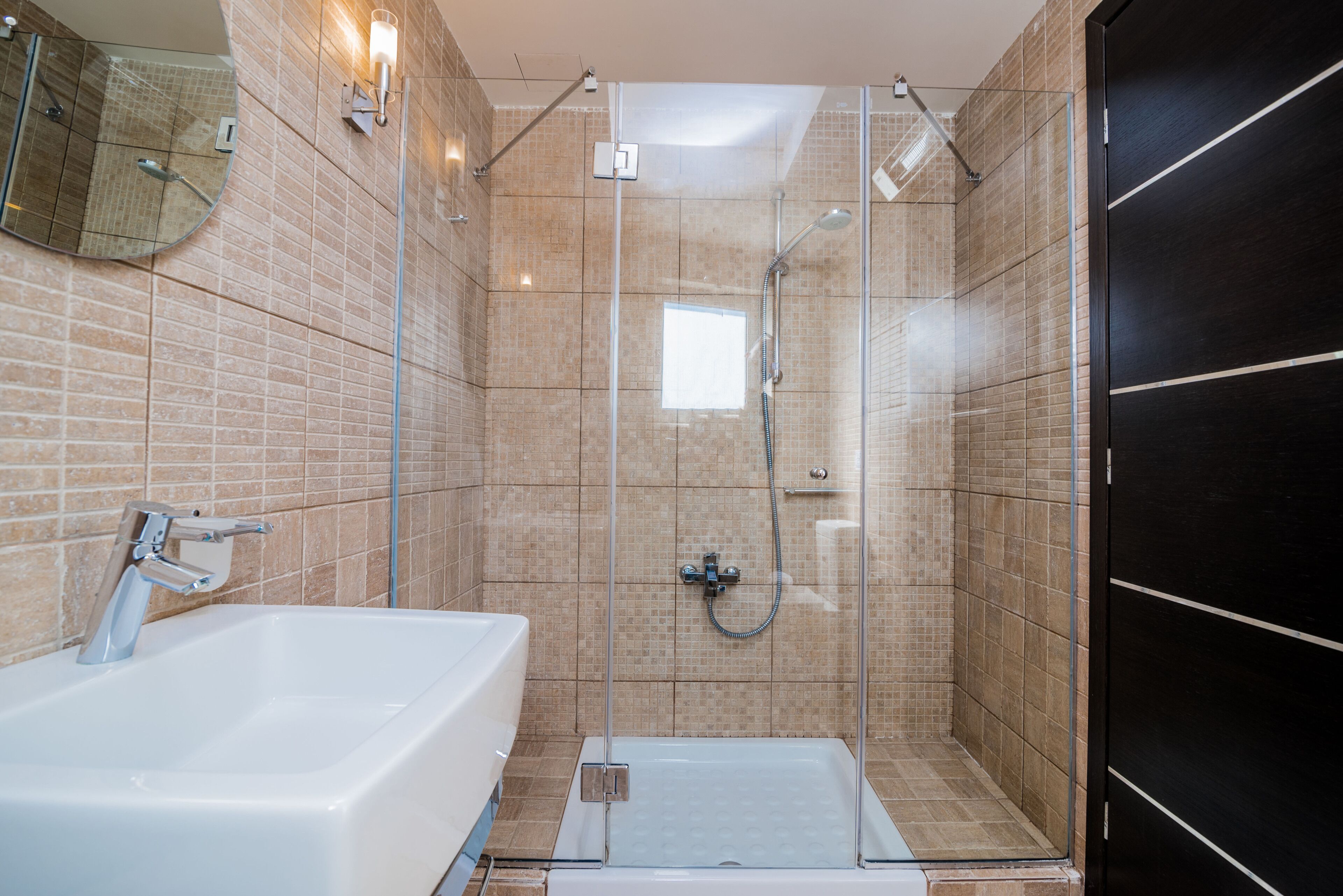 Un baño moderno con ducha de vidrio, una bañera blanca y un espejo grande.