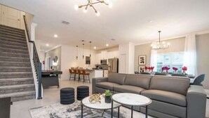 Ein modernes Wohnzimmer mit einem grauen Sofa, einem runden Couchtisch und einer Treppe.