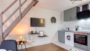 A modern kitchen with a built-in washing machine, a microwave, and a flat-screen TV. - Charmant Duplex 30 min Paris (Corbeil-Essonnes)