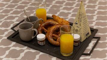 Un plateau contenant des articles pour le petit-déjeuner, notamment des croissants, des bretzels et du jus, ainsi que des condiments et un porte-serviettes.