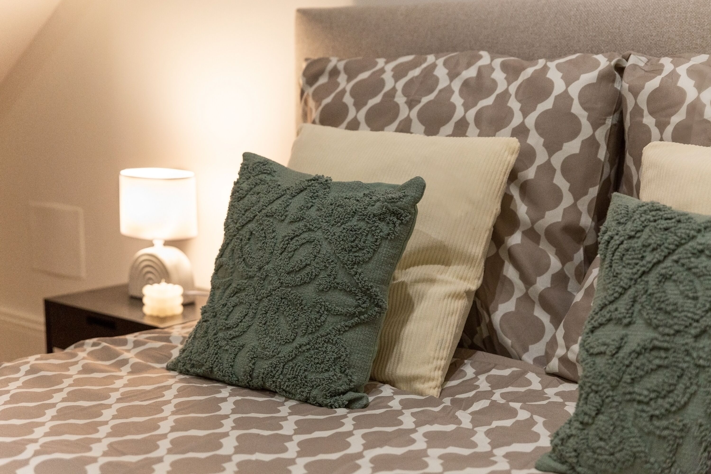 Una cama con ropa de cama estampada y almohadas decorativas.