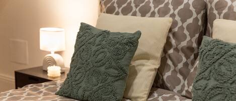 Una cama con ropa de cama estampada y almohadas decorativas.