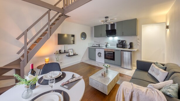 A modern apartment with a dining area, a living room, a kitchen, and a staircase. - Charmant Duplex 30 min Paris (Corbeil-Essonnes)