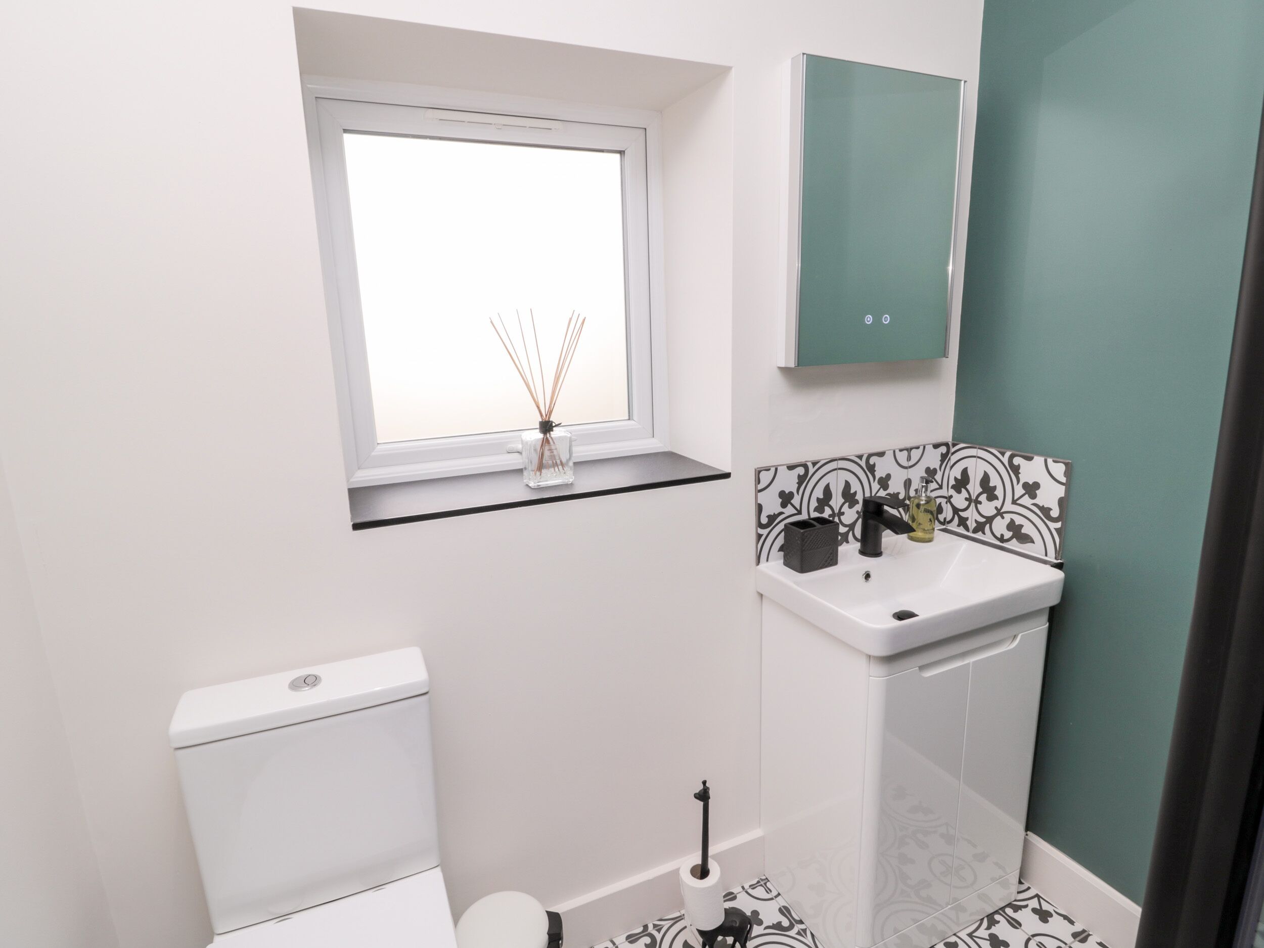 Une petite salle de bain avec des toilettes, un lavabo et une fenêtre située au-dessus du lavabo.