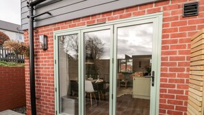 Ein Backsteinhaus mit einer großen Schiebetür, die auf eine Terrasse führt.